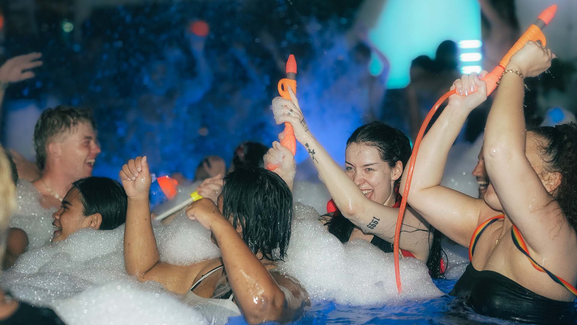 Guests celebrating Songkran at a lively Koh Samui pool party with water guns and foam
