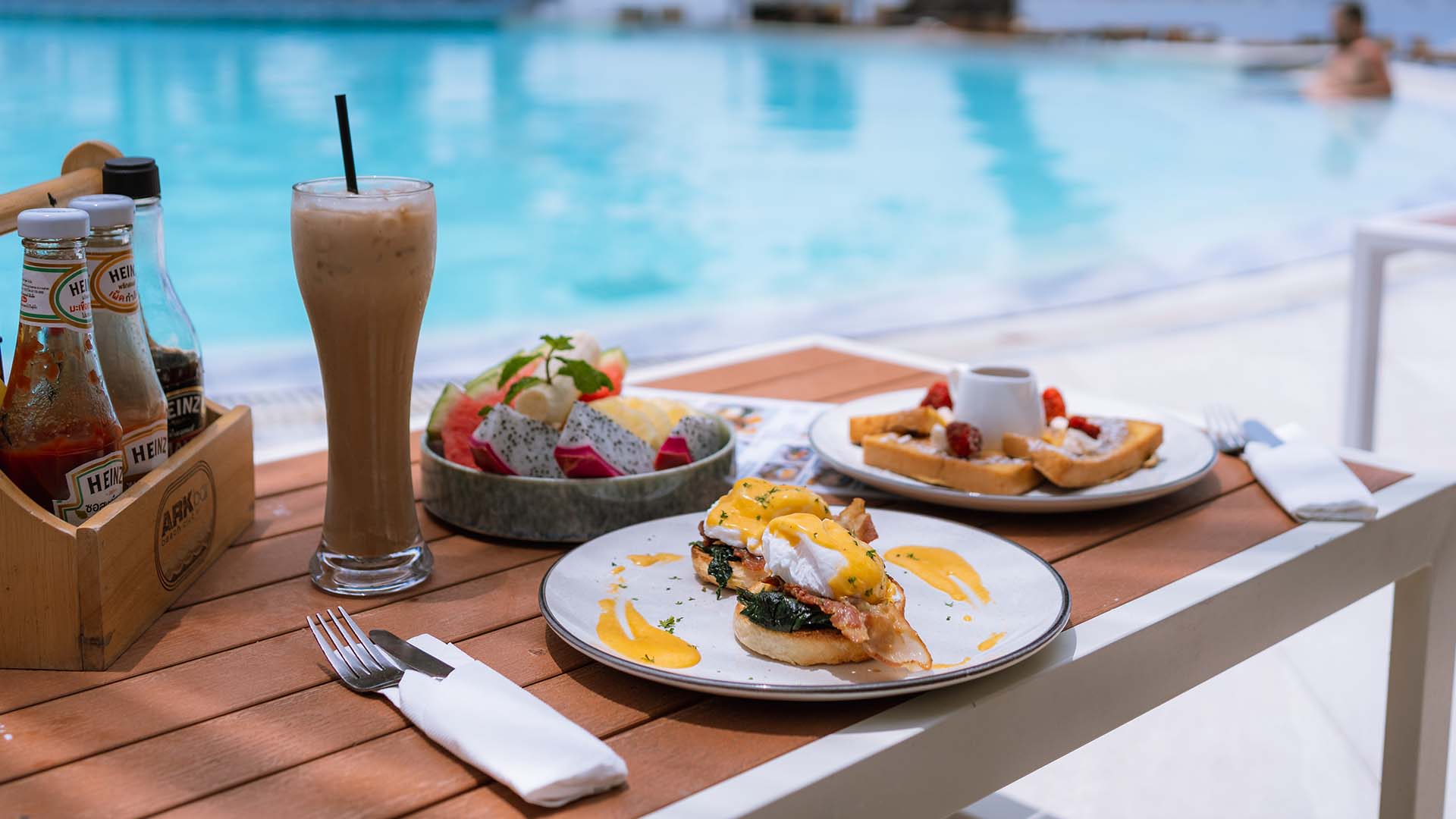 Breakfast with ocean view at ARKbar Beach Club on Chaweng Beach — eggs benedict, french toast, fresh fruit and iced coffee served by the pool.